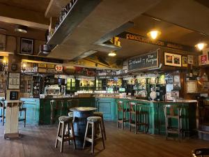 都柏林渡船夫酒店的一间设有绿色橱柜和凳子的酒吧