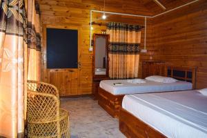 尼拉瓦利Mithra Paradise Beach Hotel的小木屋内一间卧室,配有两张床