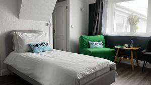 霍利黑德Orient B&B的一间卧室配有一张床和两张绿色椅子