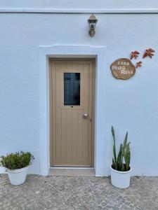 法鲁Casa Pedra Rosa - VINHAS de NEXE的两棵盆栽植物的白色建筑的门