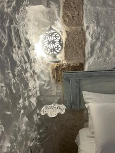奥斯图尼Dimora L’Antico Bijou的一间卧室设有石墙、一盏灯和一张床