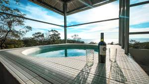MéridaVilla Ometepe的游泳池畔的桌子上坐着一瓶葡萄酒