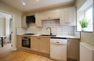 MoortownStunning luxury 3 bed house with garden in North Leeds的厨房配有白色橱柜、水槽和洗碗机。
