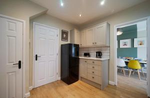 MoortownStunning luxury 3 bed house with garden in North Leeds的厨房配有白色橱柜和黑色冰箱。