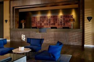 洛杉矶艾美德尔菲娜圣莫尼卡酒店的大堂设有蓝色椅子和大屏幕