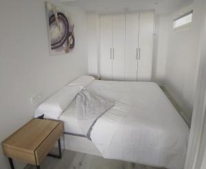 昂代Appartement à Hendaye avec piscine et à côté de la plage的一张白色的床,位于一个配有木桌的房间