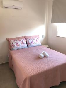 因巴塞Conforto e Aconchego em Imbassaí/BA的一间卧室配有粉红色的床和2条毛巾