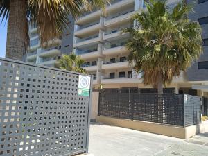阿尔么丽亚Piso nuevo con piscina cerca de parque las familias y playa de Almeria的棕榈树建筑前的围栏