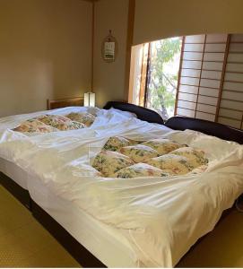 佐野市Rokugatsu-no-Mori Auberge的一张白色的床,上面有很多枕头