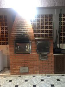伊瓜苏Casa em Foz do Iguaçu的砖墙上带两个显示器的砖砌壁炉