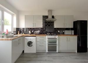 RobyFree Parking Large House Huyton Golf Club M57的厨房配有白色橱柜和炉灶烤箱。