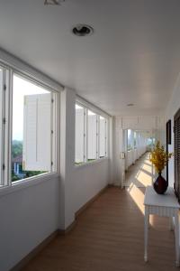 华欣Seapine Beach Golf and Resort Hua Hin的走廊上设有白色的墙壁、窗户和桌子
