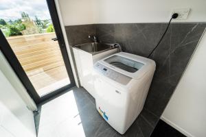 奥克兰Modern Howick Town House Fibre WiFi Netflix的一间带盥洗盆的浴室内的洗衣机