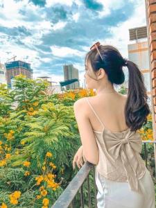 岘港Anstay Homestay & Apartment的站在围栏上看着鲜花的女人