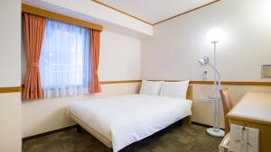 太田市Toyoko Inn Gumma Ota eki Minami guchi的卧室配有白色的床和窗户。