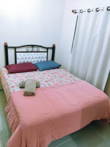 里奥格兰德Casa Excelente Localização!的一张带粉红色棉被的床和两张毛巾