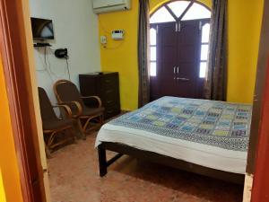 AguadaAlexmarie Guest house 5 min to candolim Beach的一间卧室配有一张床、两把椅子和一个窗户