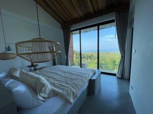 西塔努Villa Nour - 3 BR sea view pool villa in Srithanu的一间卧室设有一张床和一个大窗户