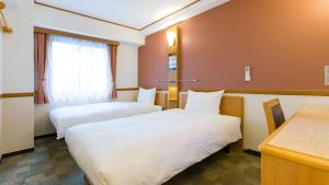 横滨Toyoko Inn Shin-yokohama Ekimae Honkan的酒店客房配有两张床和一张书桌