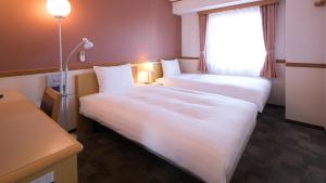 米泽市Toyoko Inn Yonezawa Ekimae的酒店客房设有两张床和窗户。