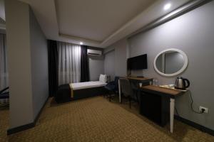 梅尔辛Eniza Hotel的酒店客房带一张床、一张书桌和一面镜子