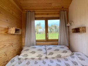 Roulottes des terres de la chouette的木制客房的一张床位,设有窗户
