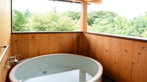 富士河口湖HOTORI no HOTEL BAN的带浴缸的浴室和窗户