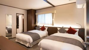 富士河口湖HOTORI no HOTEL BAN的酒店客房,设有两张床和镜子