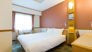 苫小牧市Toyoko Inn Hokkaido Tomakomai Ekimae的一间酒店客房,配有一张白色的床和一张书桌