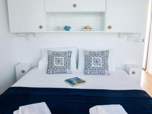 夫塞塔Barco Casa Fuzeta的一张带蓝色枕头的白色床和一本书