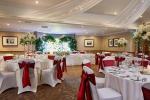 格兰奇茅斯农庄庄园酒店的宴会厅设有白色桌子和红色弓