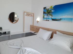 希马拉Anxhelos Hotel的卧室配有白色的床,享有海滩美景