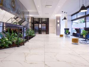 比尔比尔美居酒店的办公室大堂铺有白色大理石地板,种植了植物