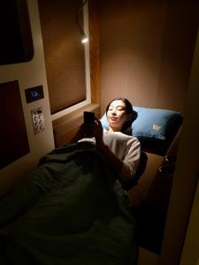 多哈sleep 'n fly Sleep Lounge & Showers, NORTH Node - TRANSIT ONLY的躺在床上看手机的女人