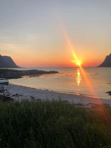 RystadRystad Lofoten Camping的日落在海滩上,阳光在水面上