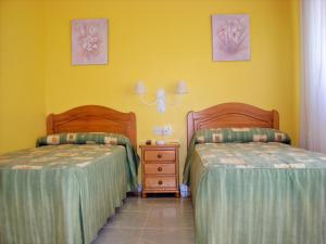 巴约讷Hostal Santa Marta Playa的黄色墙壁客房的两张床