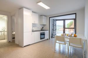 阿尔巴塔克斯Cosy and Modern Apartment Portu Frailis的厨房配有白色橱柜和桌椅