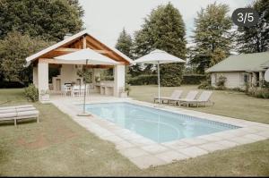安德伯格Elgin Guest House的一个带两把遮阳伞和房子的游泳池