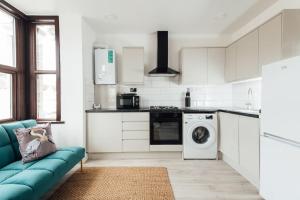 依尔福Modern 2 Bedroom Flat in Ilford, London的厨房配有蓝色的沙发和洗衣机
