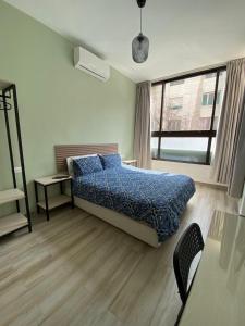 安曼Arabesque Hotel的一间卧室配有一张带蓝色棉被的床和窗户。