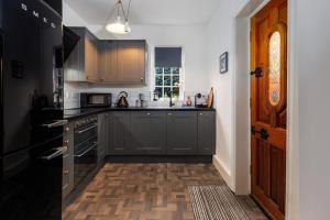 利物浦Air Host and Stay - Anfield cottage, 2 bedroom 2 bathroom的厨房铺有木地板,配有灰色橱柜。