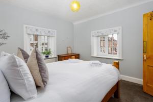 利物浦Air Host and Stay - Anfield cottage, 2 bedroom 2 bathroom的卧室配有带枕头的白色床和2扇窗户。