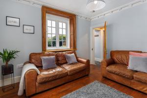 利物浦Air Host and Stay - Anfield cottage, 2 bedroom 2 bathroom的客厅配有两张真皮沙发和一个窗户