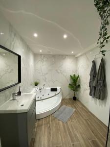 蒙斯Capsule Groovy-Jacuzzi-Sauna-Billard-Netflix- Nintendo Switch & Jeux的白色的浴室设有浴缸和水槽。