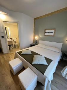 格拉多蕾佳娜酒店的一间卧室配有一张大床和两张白色凳子