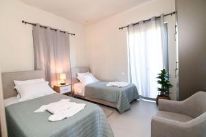 扎金索斯镇Villas Thalia的一间卧室设有两张床、一把椅子和一个窗户。