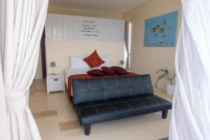 龙目岛库塔Villa Atas Pelangi的一间卧室配有一张带黑色皮革长凳的床