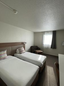 勒布朗-梅尼尔布朗梅尼尔钟楼酒店的酒店客房设有两张床和窗户。