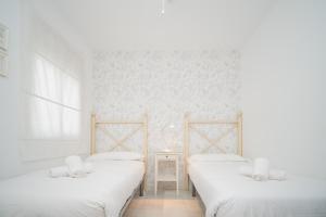 桑卢卡尔-德巴拉梅达Sol y Vida, Apartamentos Living Sur的白色墙壁客房的两张床