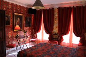 巴黎尼斯酒店的一间卧室配有红色窗帘、一张床和窗户